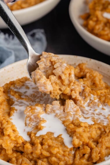 a bowl of pumpkin rice pudding being scooped with a spoon