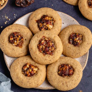 vegan baklava cookies on a plate with dates and nuts on blue background