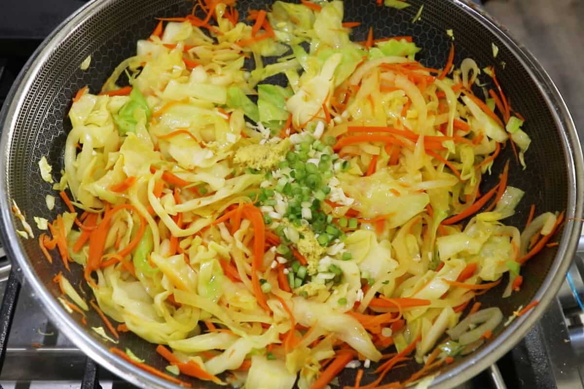 step by step of green onion, garlic, and ginger being added into a wok of vegetables