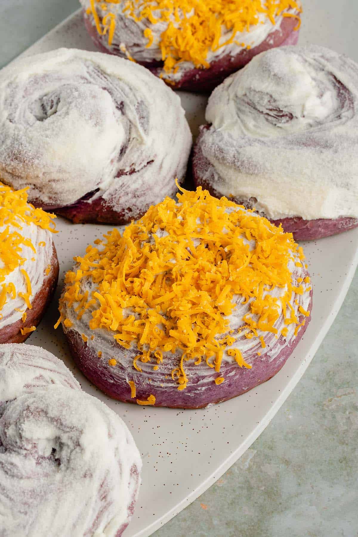 photo of ube ensaymada with cheddar cheese on a white serving platter
