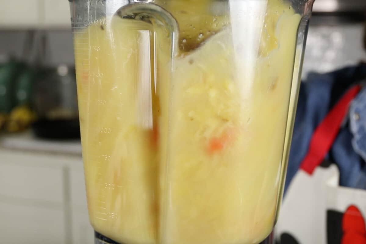 blending water, oranges, lemons, pineapple, ginger, carrots, garlic, water, agave, turmeric and black pepper