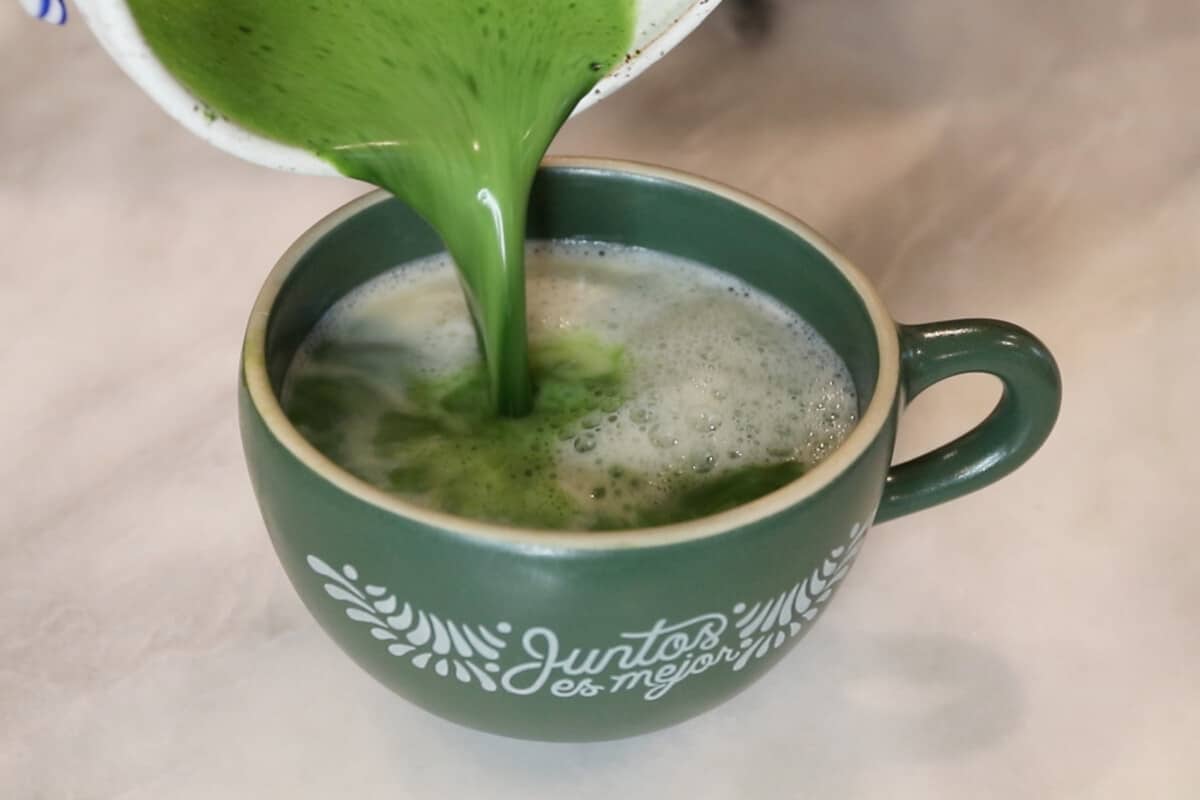 pouring prepared matcha into mug with milk