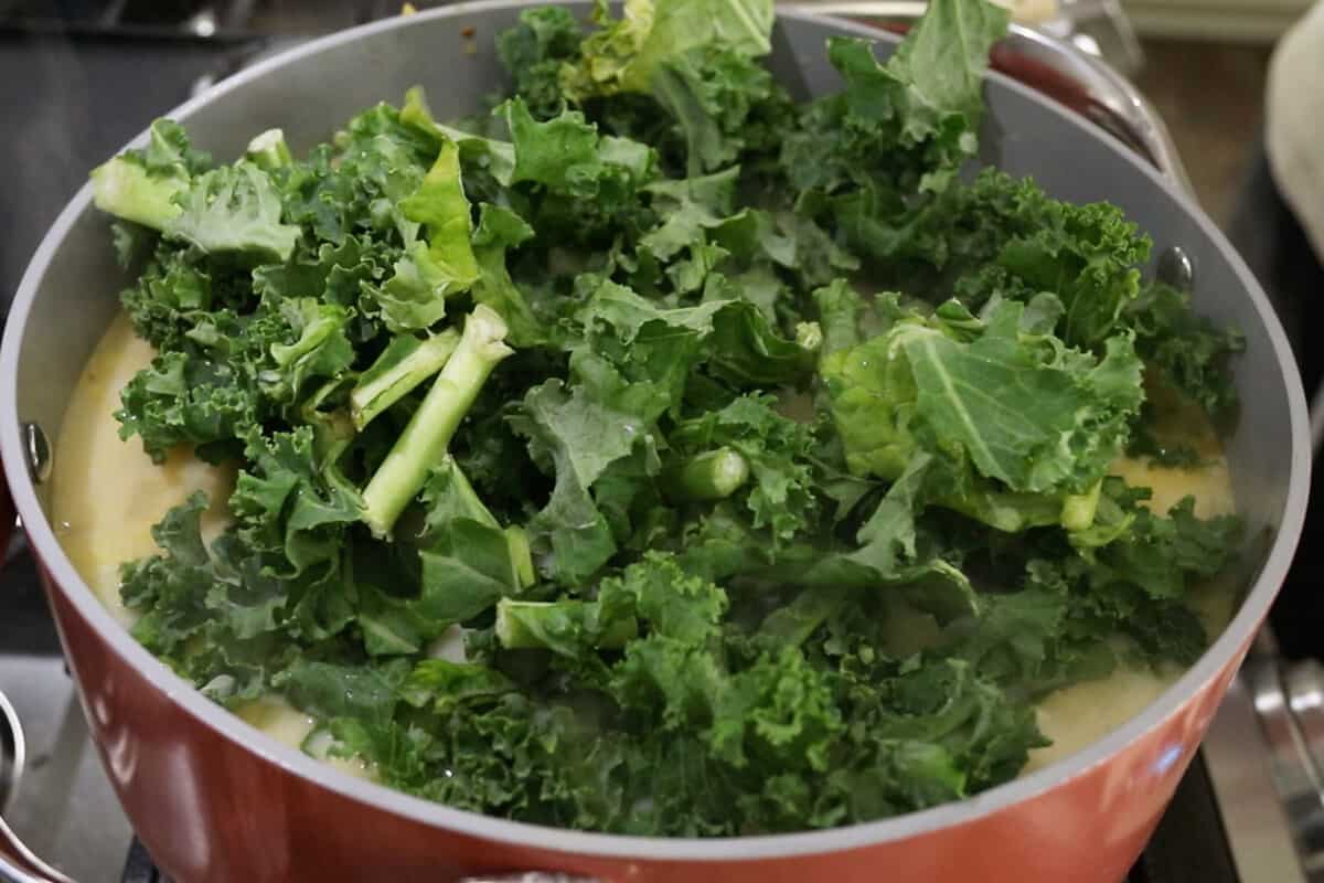kale being added to pot of soup
