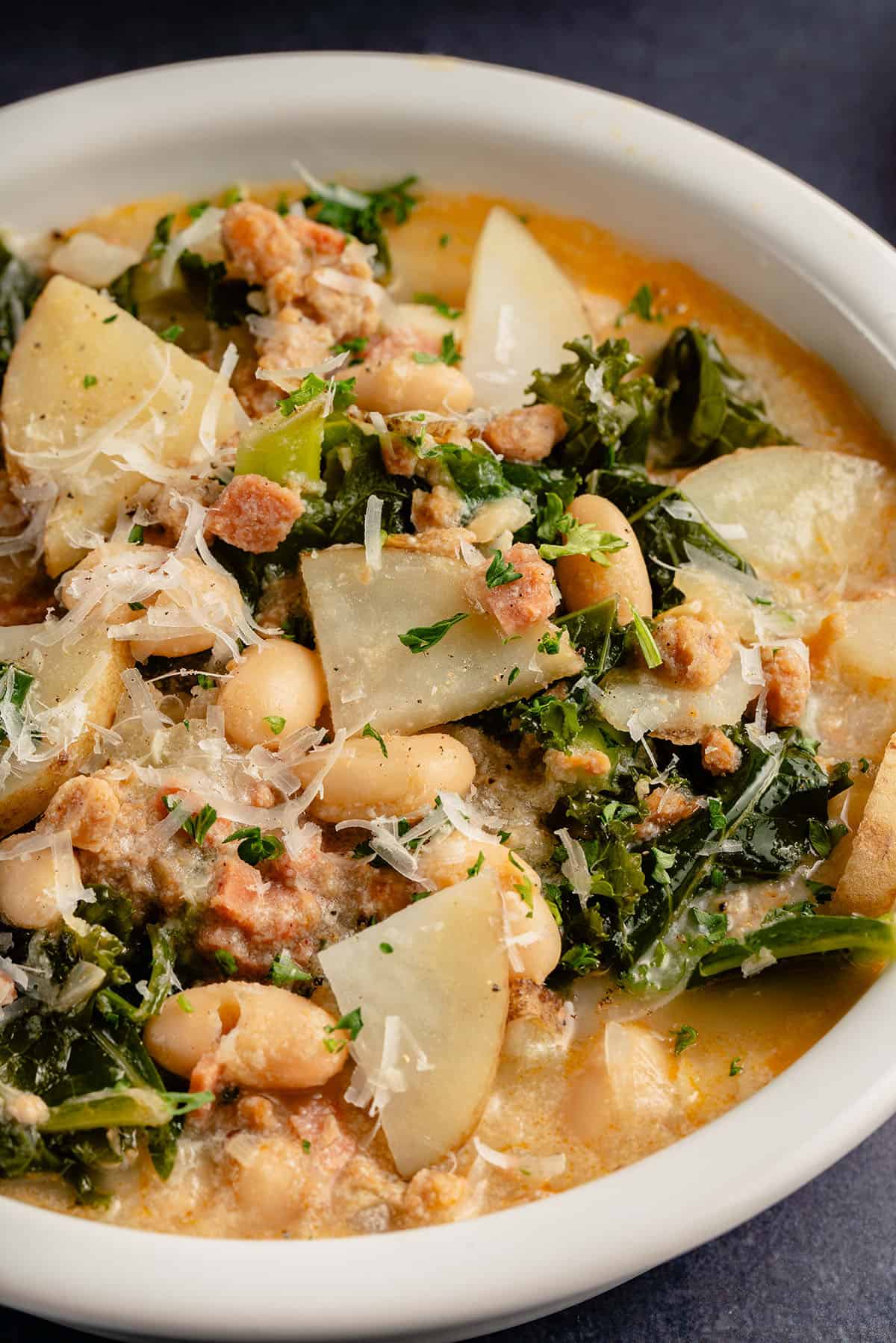 upclose image of vegan zuppa toscana topped with parmesan cheese in white bowl