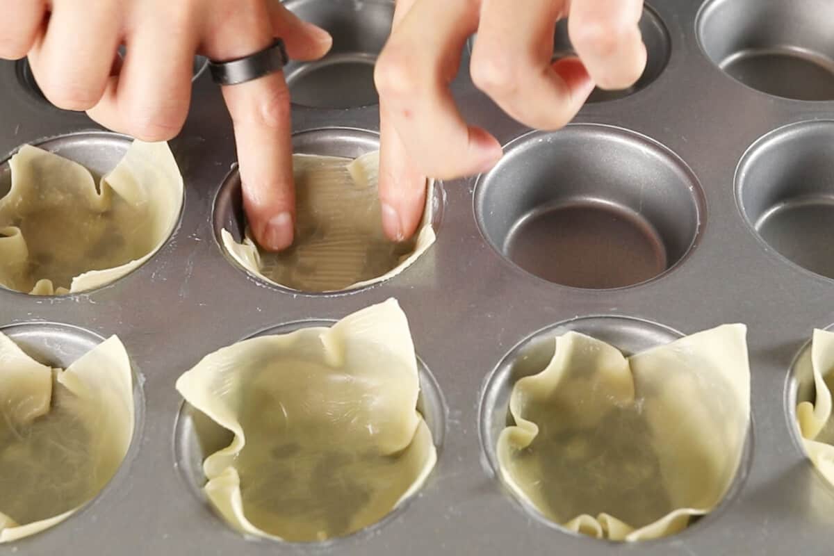 step by step - wonton wrapper being pressed into cupcake tin
