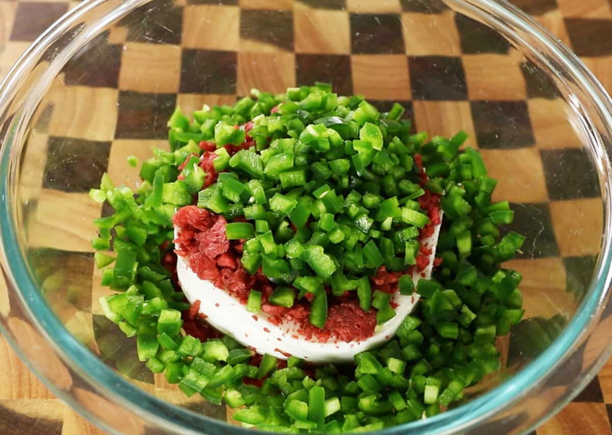step by step - jalapenos in glass bowl with vegan cream cheese and bacon bits