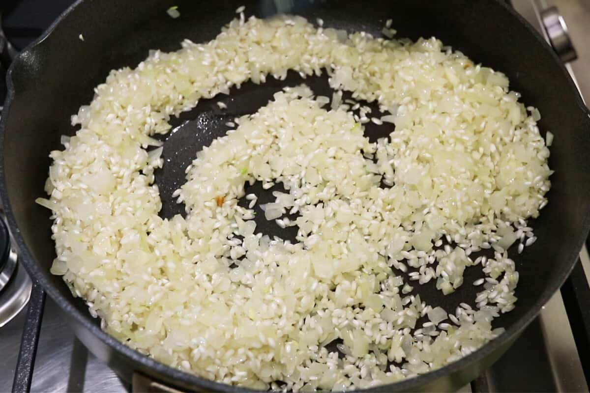 onions and rice being cooked in pan