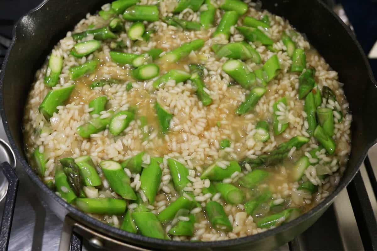 asparagus being mixed into the pot of risotto