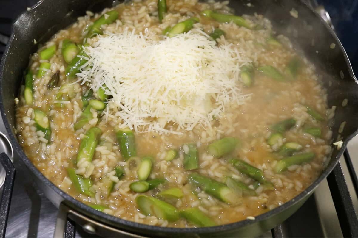 vegan parmesan cheese being added to the pot of risotto