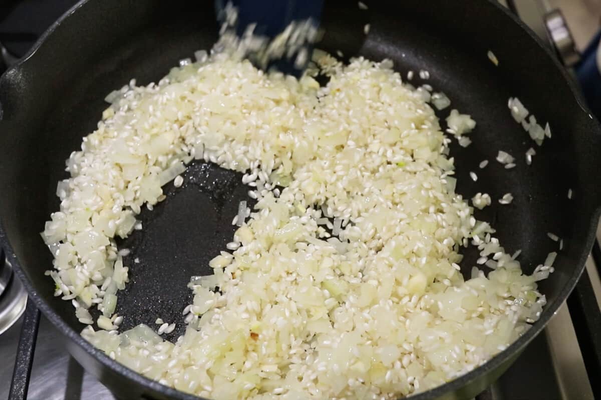 onions and rice being mixed together in a pan