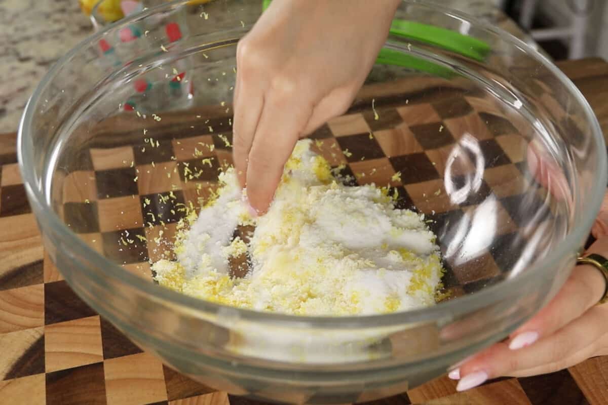 mixing fresh lemon zest with sugar by hand to release natural oils for lemon loaf