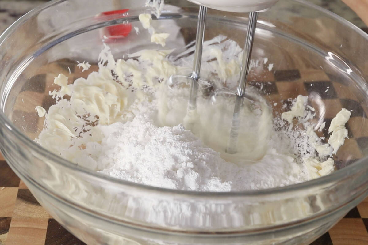 step by step: using a hand mixer to whip the powdered sugar into the butter to make buttercream frosting
