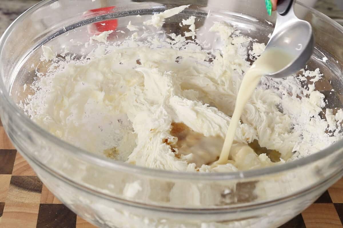 step by step: adding milk to glass bowl to thin out frosting