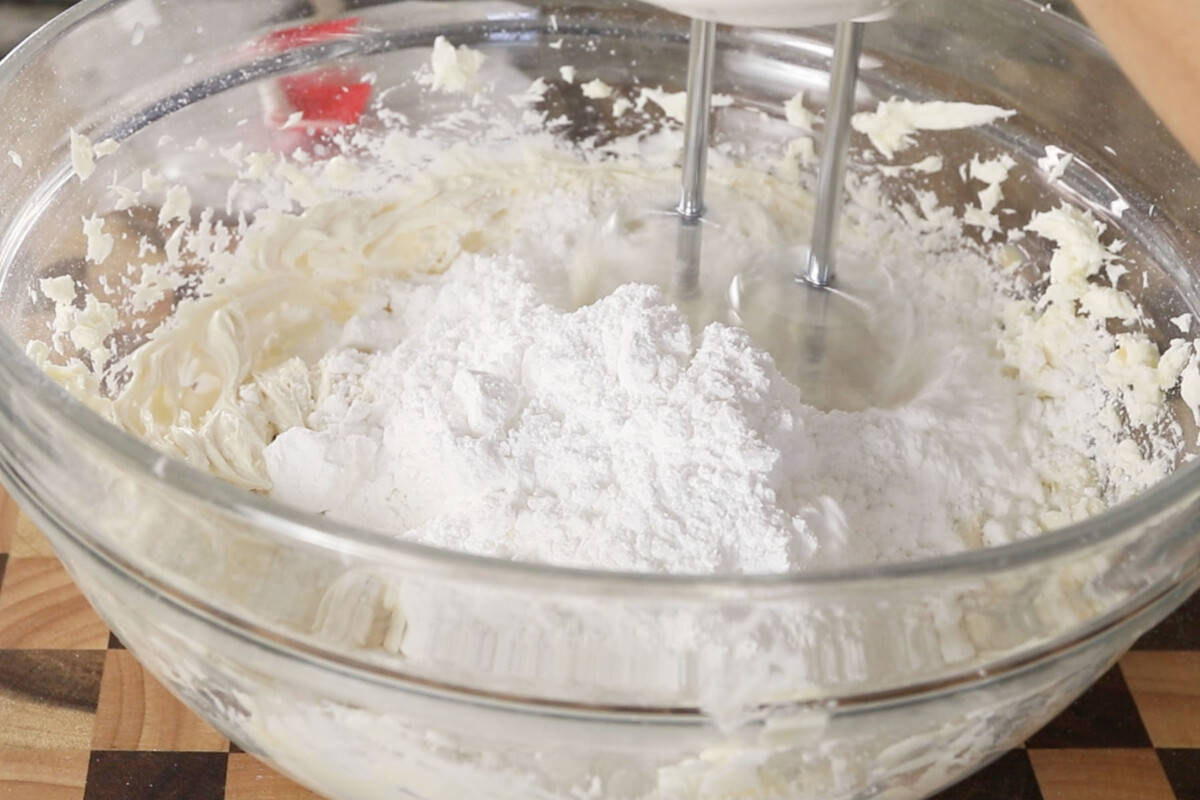 step by step: adding more powdered sugar to glass bowl