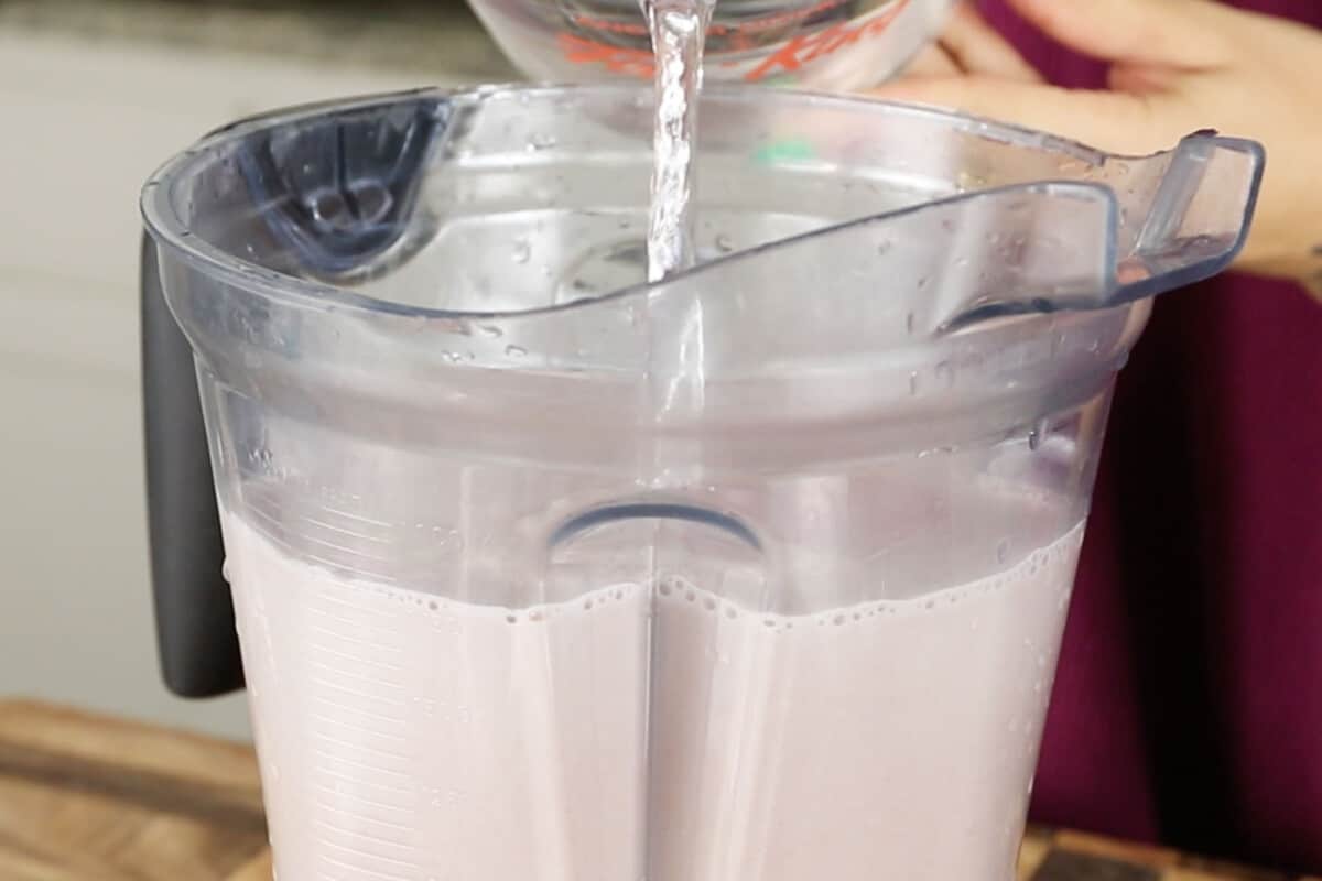 adding water into blender with ube horchata to water it down before serving