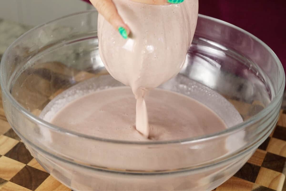 straining ube horchata mixture into glass bowl