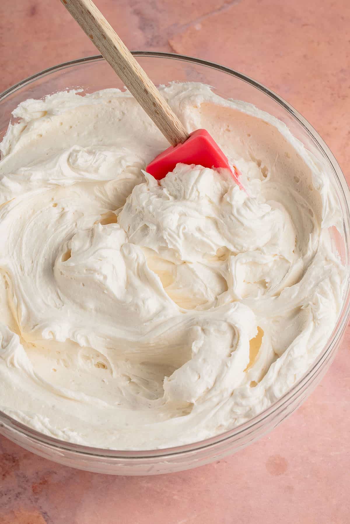 bowl of vanilla buttercream frosting with pink spatula inside