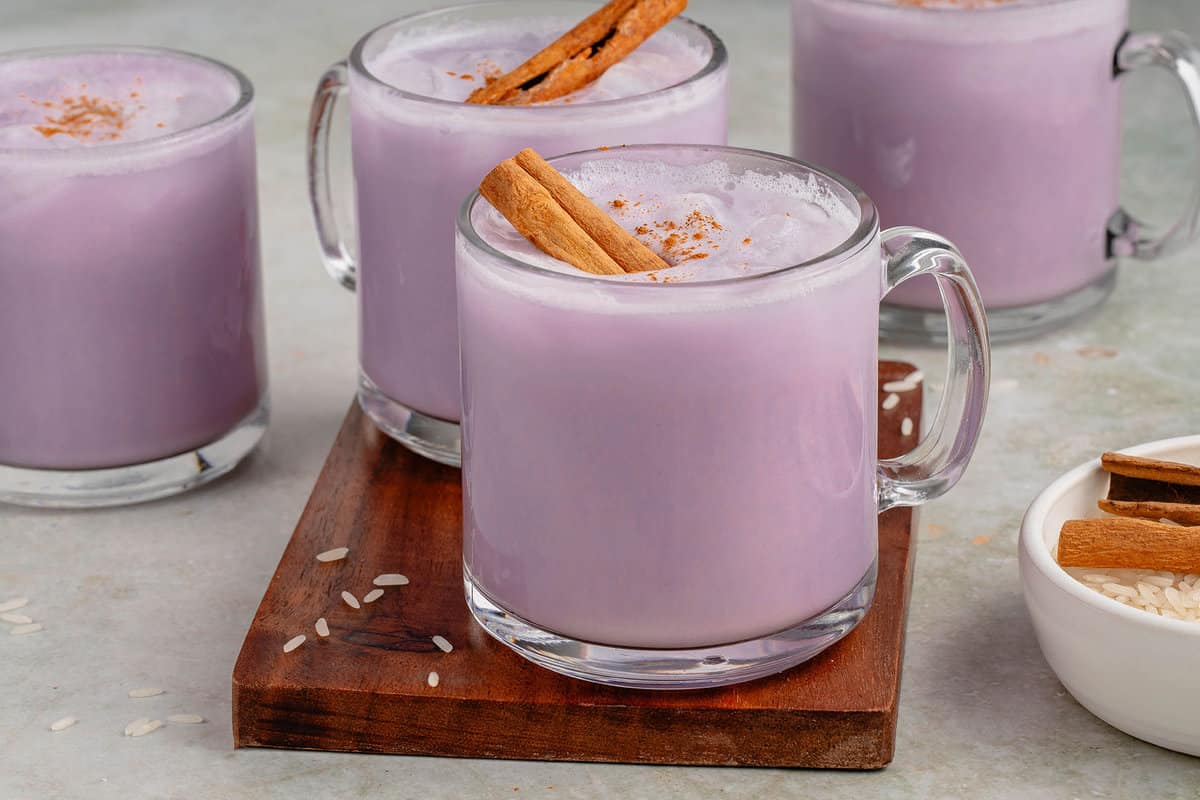 horizontal photo of 4 glasses of ube horchata styled on wooden cutting board