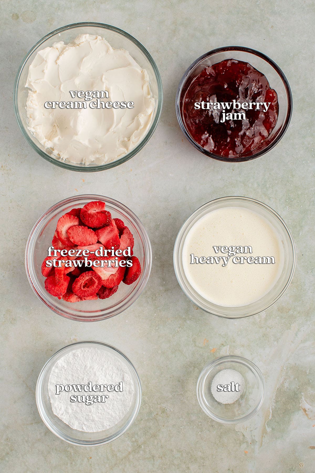 labeled ingredients for vegan strawberry mousse: vegan cream cheese, strawberry jam, freeze dried strawberries, vegan heavy cream, powdered sugar and salt