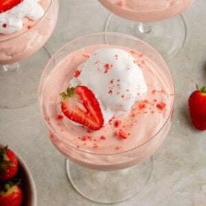 3 glasses of fluffy pink vegan strawberry mousse with whipped cream and fresh strawberries