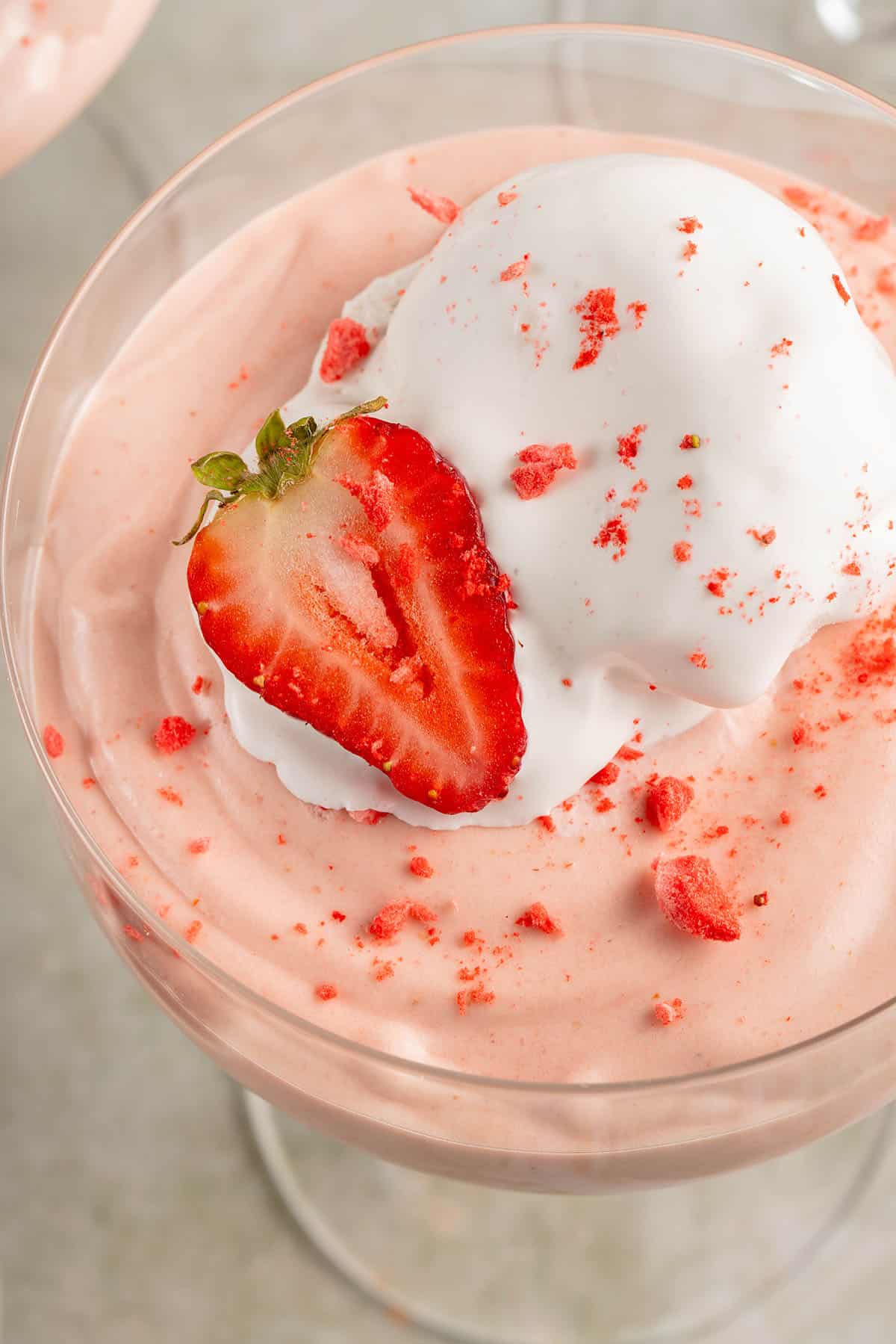 close up photo of fluffy pink vegan strawberry mousse with whipped cream and fresh strawberries
