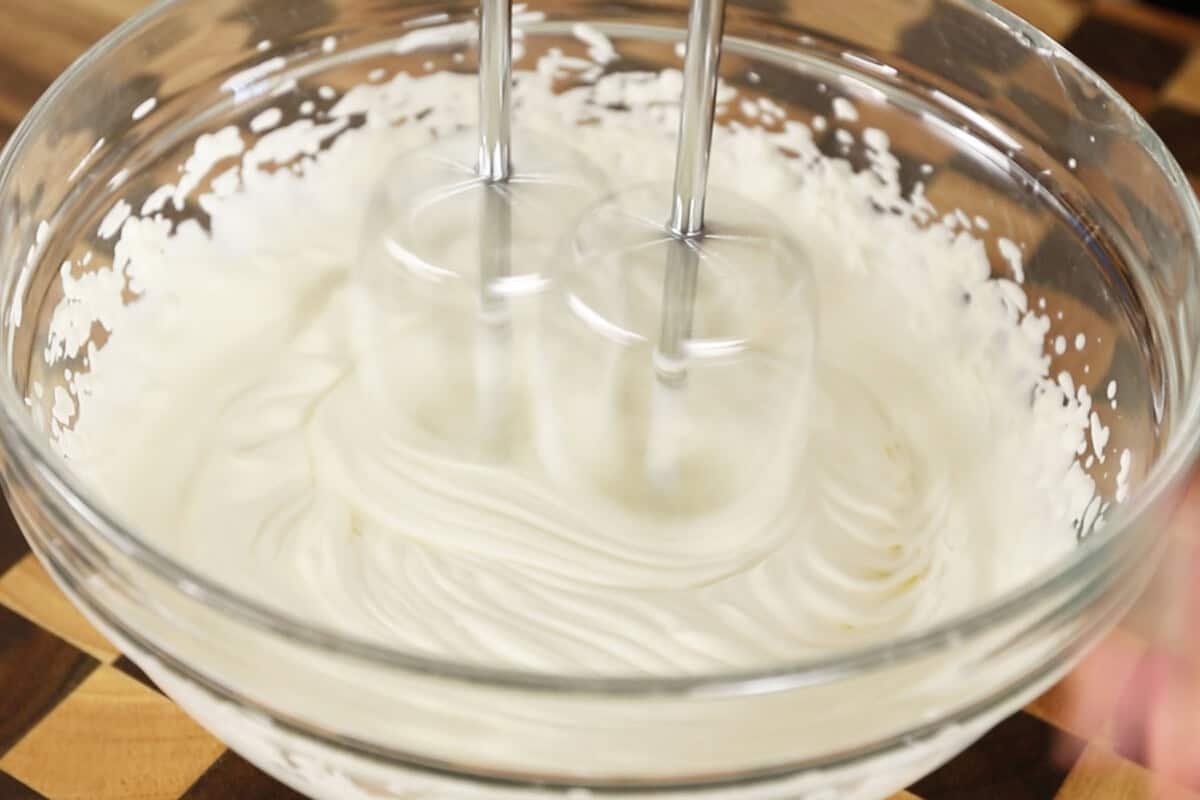 whipping vegan heavy cream in large glass bowl