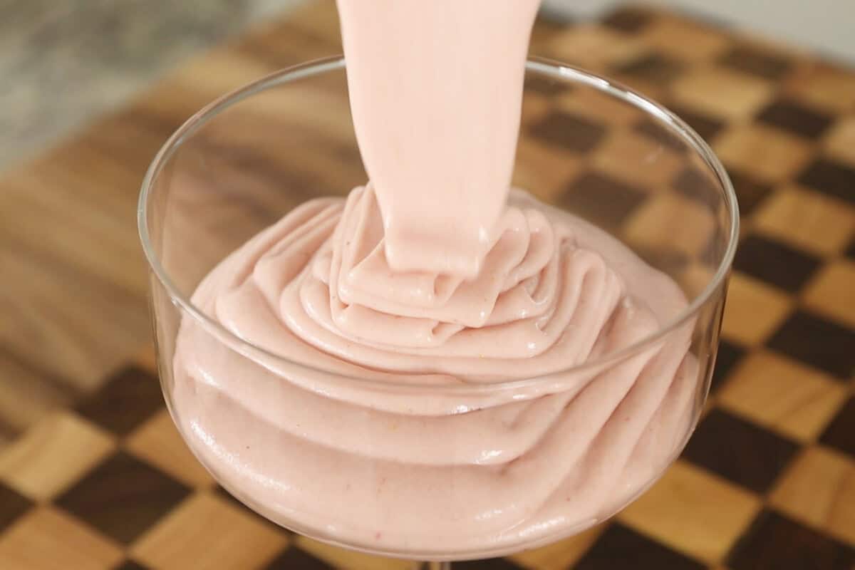 pouring fluffy vegan stawberry mousse in glass serving cup