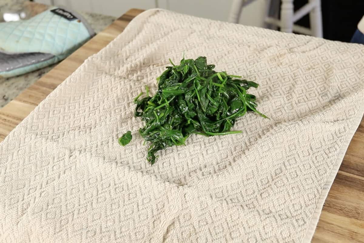 spinach in clean kitchen towel before removing liquid