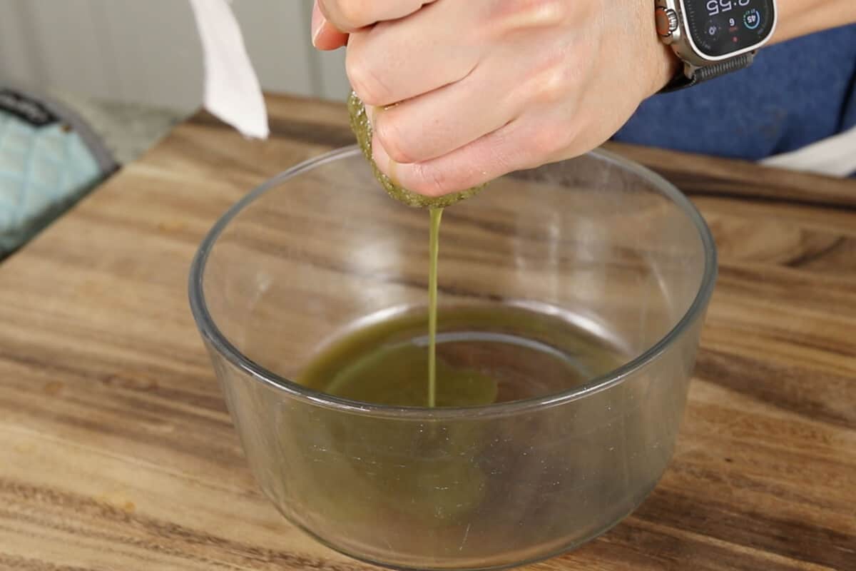 squeezing liquid out of cooked spinach into glass bowl