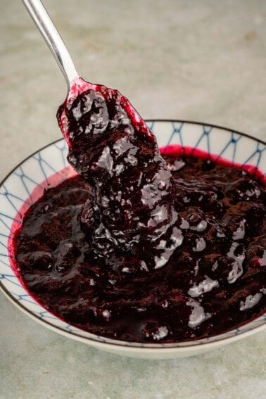 metal spoon scooping blueberry compote out of bowl