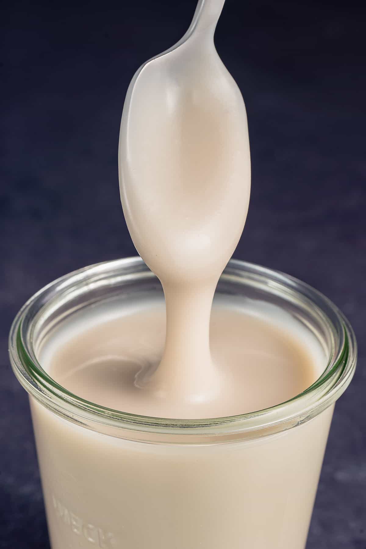 a spoonful of condensed milk dripping back into jar