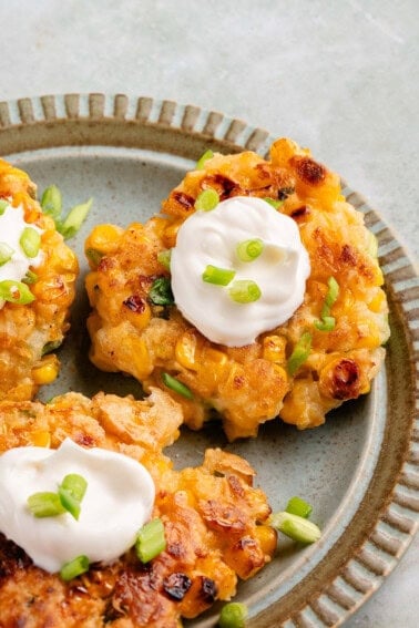 vegan corn fritters on blue plate with mayo and scallions
