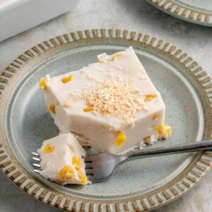 a slice of maja blanca topped with toasted coconut flakes on a blue plate