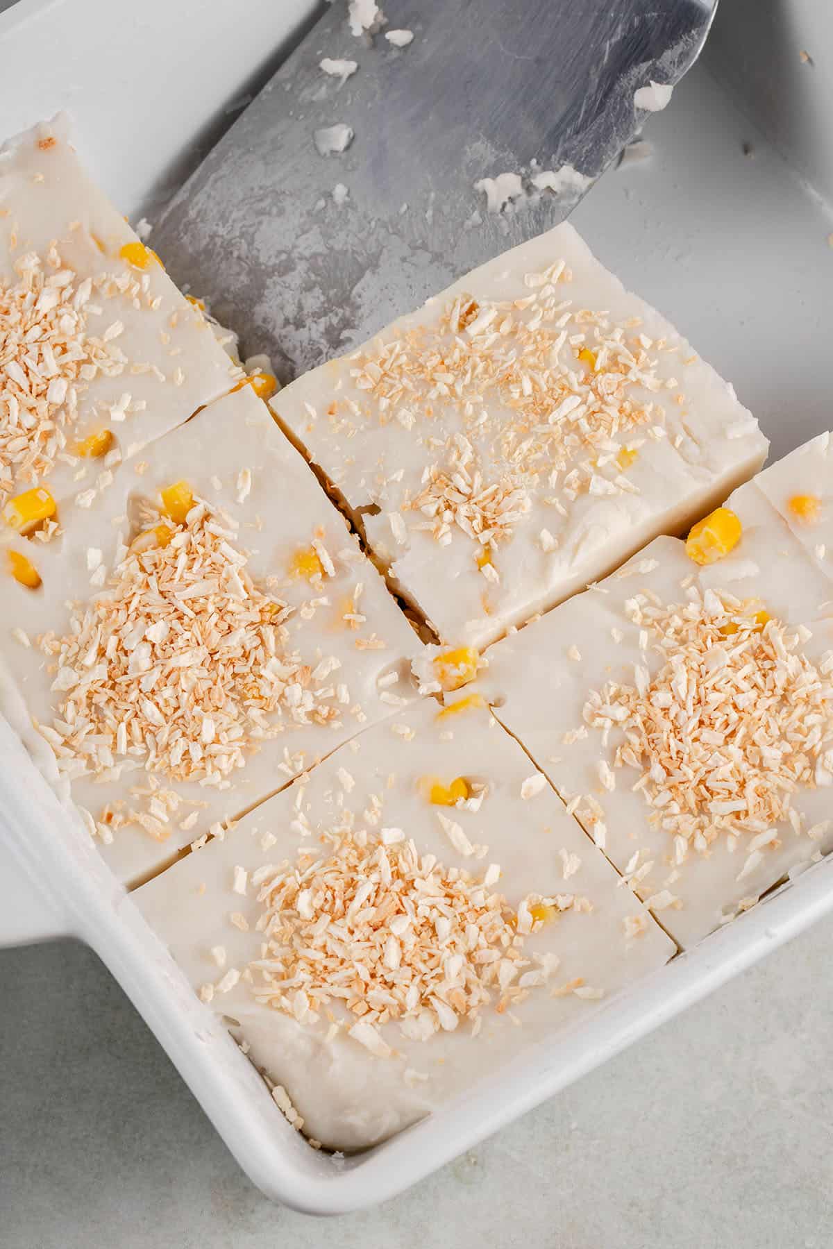 a tray of sliced maja blanca and a spatula on the side