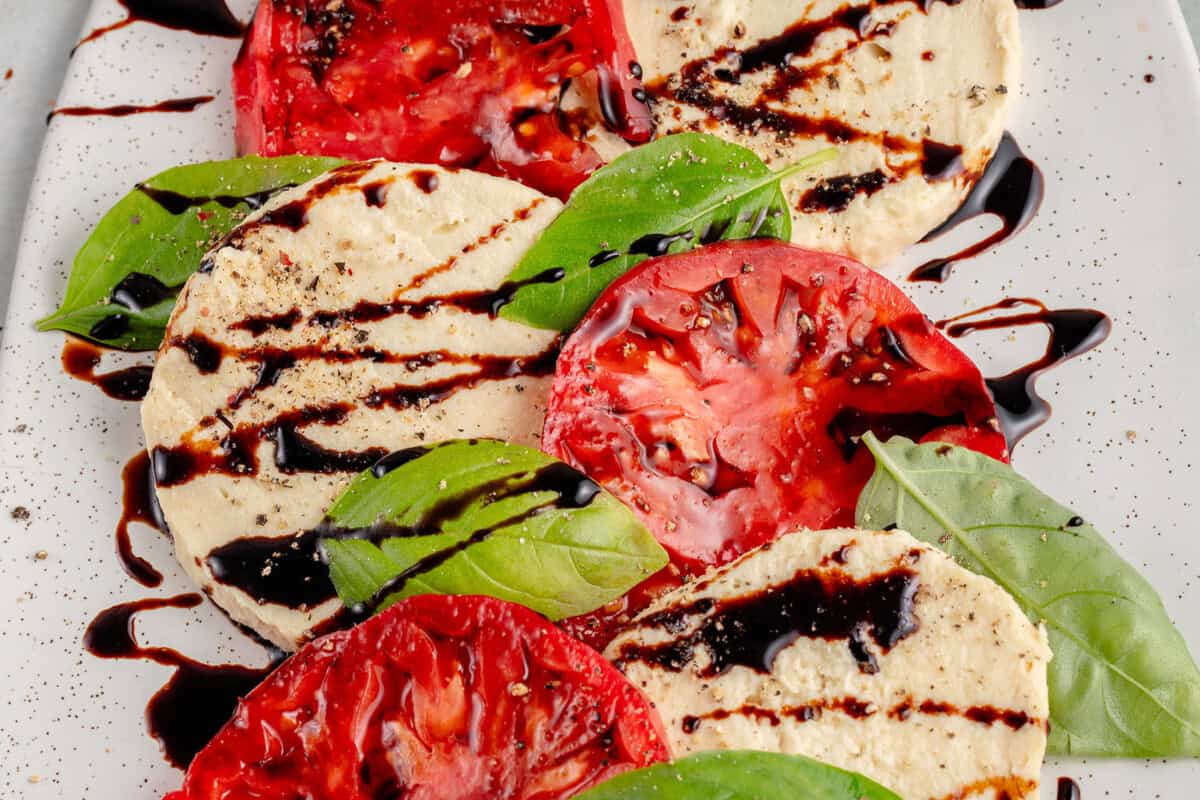 vegan mozzarella cheese with tomatoes and basil and a balsamic drizzle