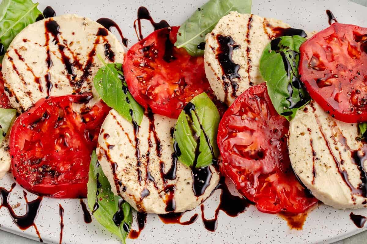 vegan mozzarella cheese with tomatoes and basil and a balsamic drizzle