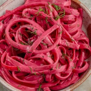close up photo of bowl of creamy Vegan Beet Pasta sauce on fettuccine topped with dill