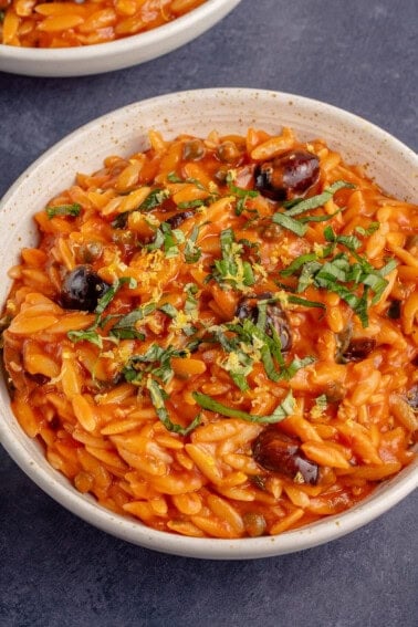 close up photo of a white bowl full of Vegan Orzo Puttanesca