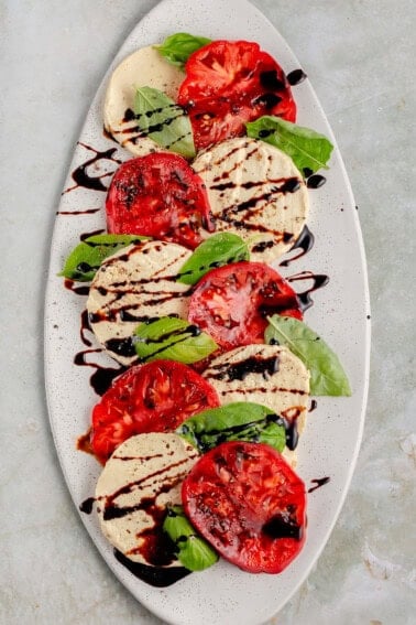 tomatoes, vegan mozzarella, basil, and balsamic drizzled on white platter