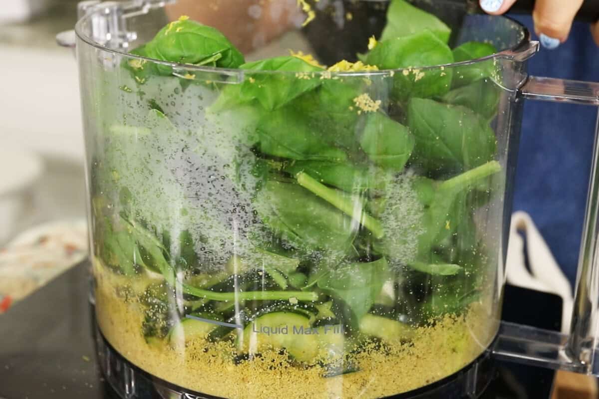 adding basil and spinach to the food processor