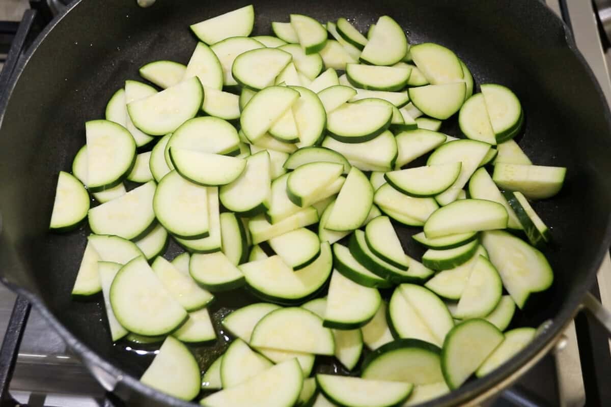adding zucchini slices to a pan