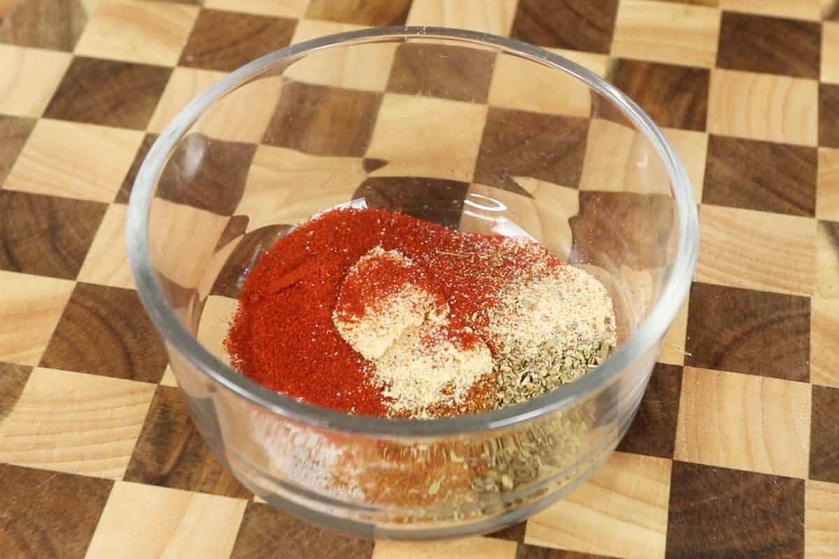 mixing together ingredients for homemade cajun seasoning in glass bowl