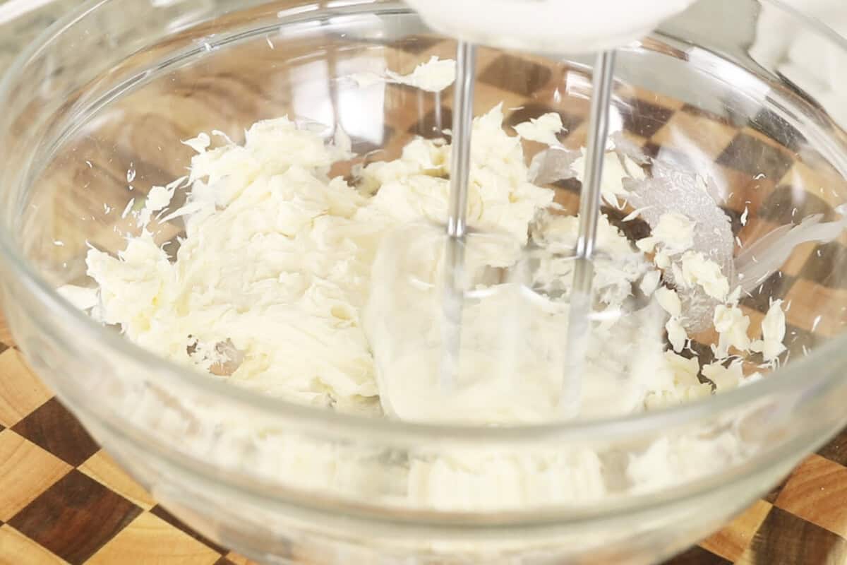 butter being mixed with a in a bowl with a hand mixer