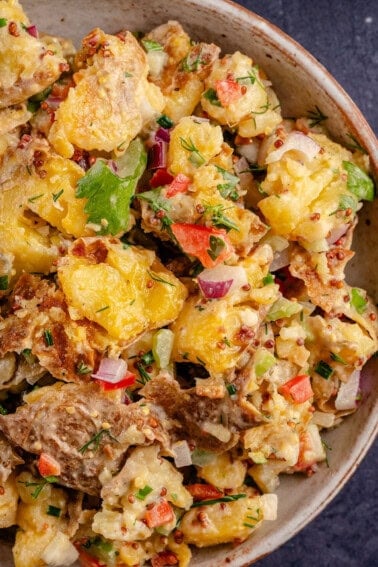 close up image of smashed potato salad in a bowl