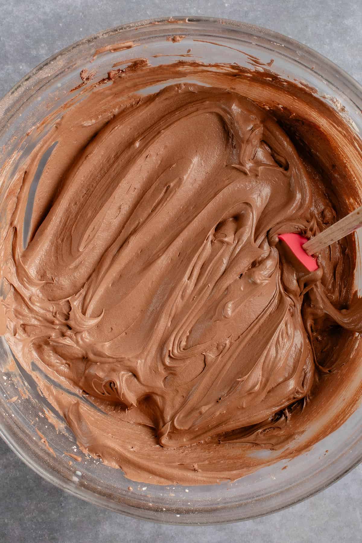 a bowl of chocolate buttercream frosting with a spatula sticking out