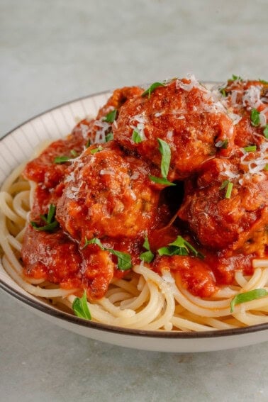 a bowl of spaghetti topped with marinara and eggplant meatballs with basil and dairy-free parm