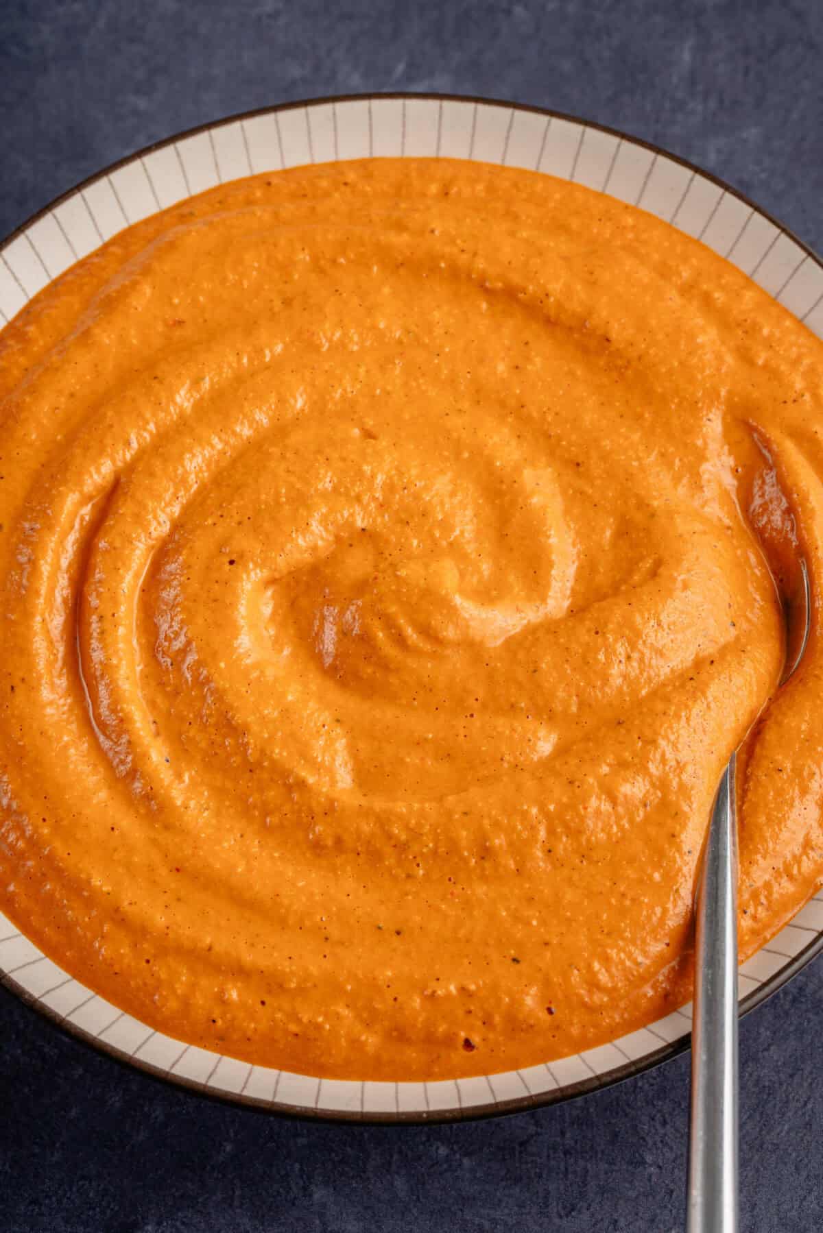 close up of romesco sauce in a bowl with a spoon