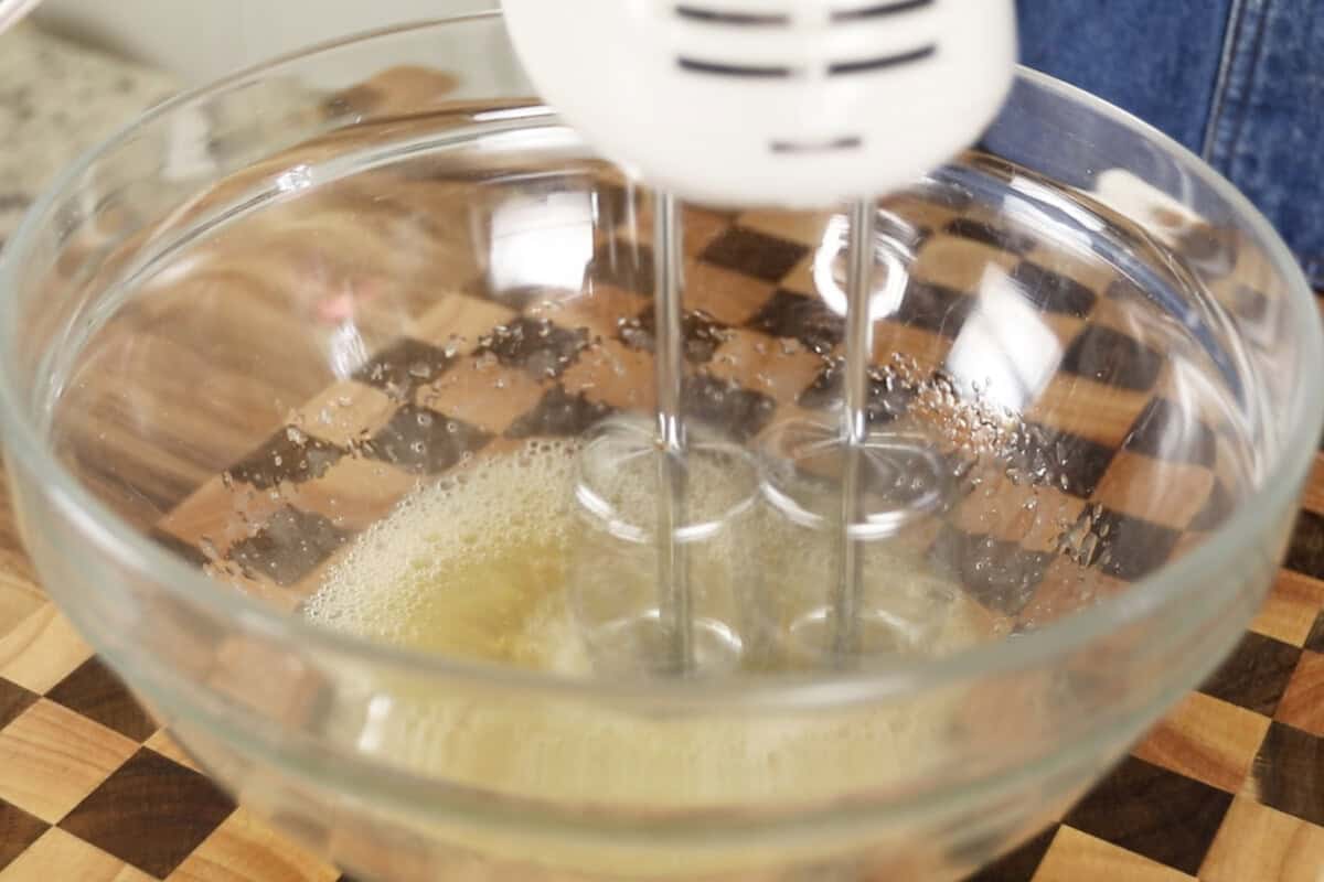 step by step: mixing the cream of tartar and aquafaba with a hand mixer in a glass bowl