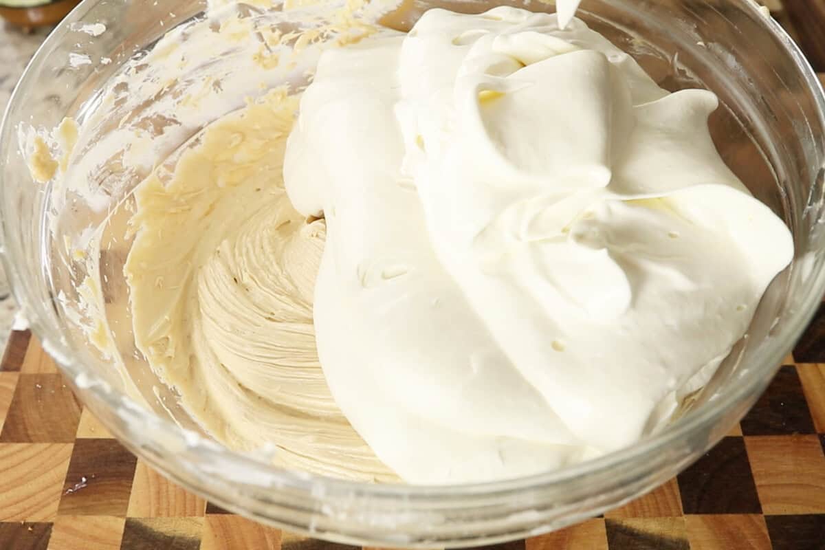 adding whipped heavy cream to a bowl