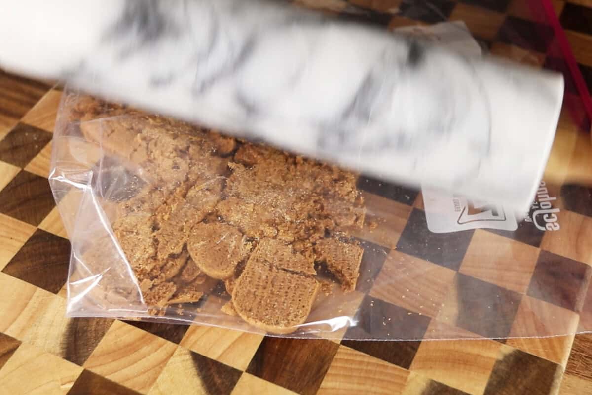 crushing biscoff cookies in a ziplock bag with a rolling pin